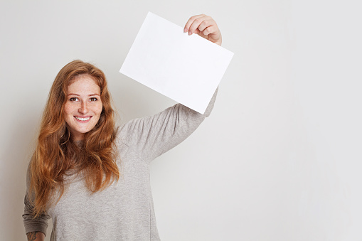 Happy woman holding empty white board on white studio background. Banner for advertising with copy space