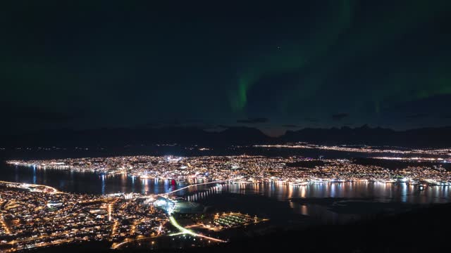 Northern Lights shining in the night sky over Tromso city in Norway