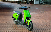Scooter vintage moto parked downtown on paved street. Bright green color eco electrical scooter