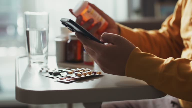 Hand holding pill bottle and talking on mobile phone,