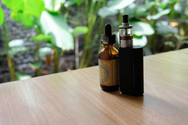 istock vape and e-cigarette liquid on wooden table 1494020993