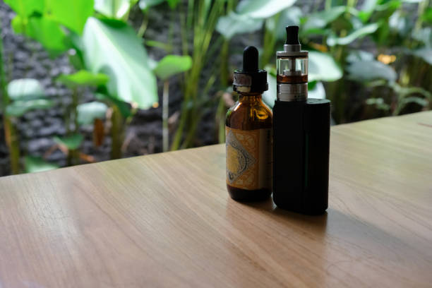 istock vape and e-cigarette liquid on wooden table 1494021046