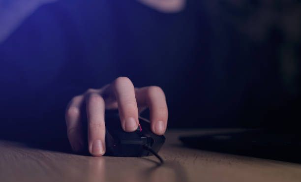 istock Close up of man gamer hands using computer mouse is playing video game at night. Male hacker breaks into system, coding or data analysis programmer, developer or employee on tech for software code 1494021048