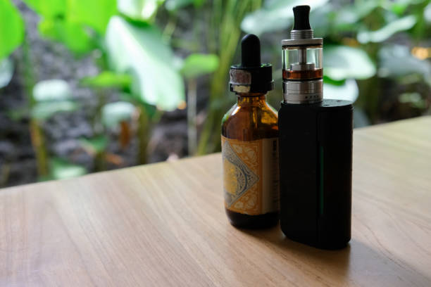 istock vape and e-cigarette liquid on wooden table 1494021062