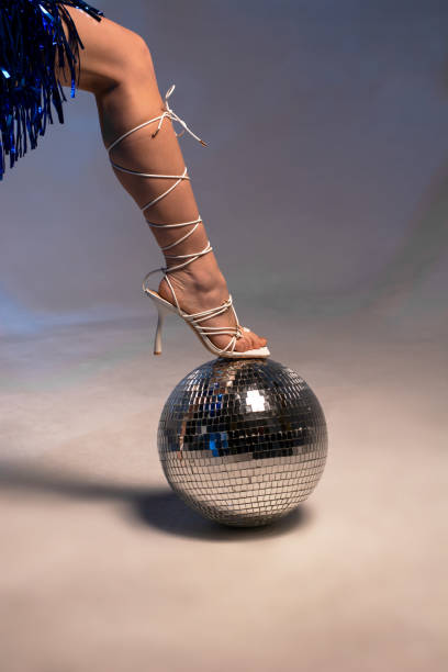 istock Female leg in beautiful white sandals on a disco ball 1494021332