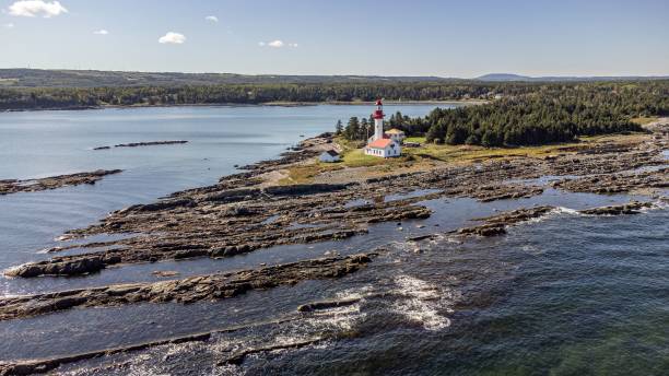 istock a lighthouse on an island with waves crashing over it and a forest in the background 1494023208
