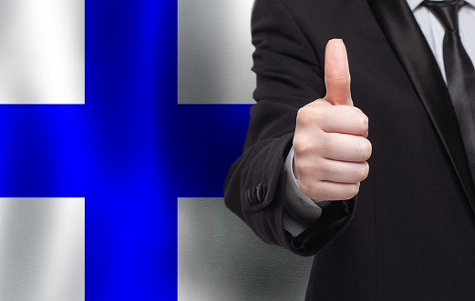 Finnish concept. Businessman showing thumb up on the background of flag of Finland