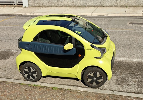 Udine, Italy. May 27, 2023. Yellow XEV Yoyo, 3D printed electric city car, at the roadside. Side view.