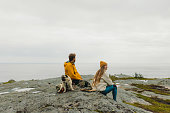 Happy woman and man with dog contemplating summer day outdoors on Lofoten Islands