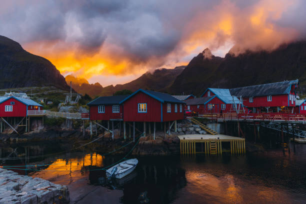 The magic of a summer night on Lofoten Islands Dramatic view of the bright colorful sky above the mountains and the old fisherman village Å with red houses and reflection sea during the Midnight Sun on Lofoten, Northern Norway midnight sun stock pictures, royalty-free photos & images