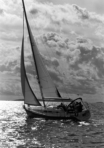 Leaning sailing boat,  black and white view with cloudscape.