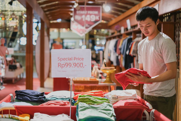 Asian Man Shopping Sale Clothes Close-up shot of Asian man taking a folded clothes from a clothing sale box at the department store. Black Friday - shopping event concept colorful check shirts on sale at a clothing store stock pictures, royalty-free photos & images