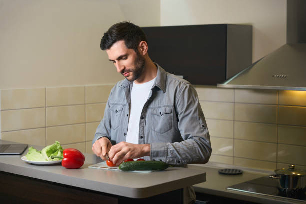 istock Middle-aged man cuts vegetables for salad on the kitchen 1494042804