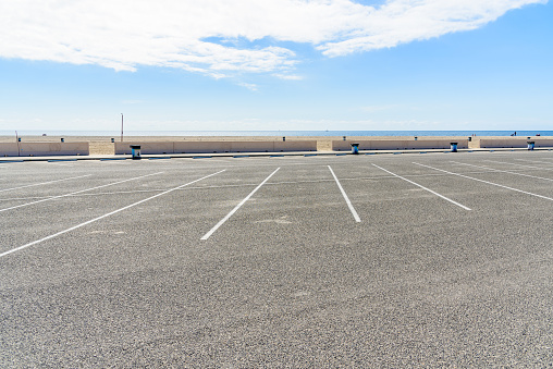 Empty car park along a sandy beach on a clear partly cloudy autumn day. Zuma beach, Malibu, CA, USA.