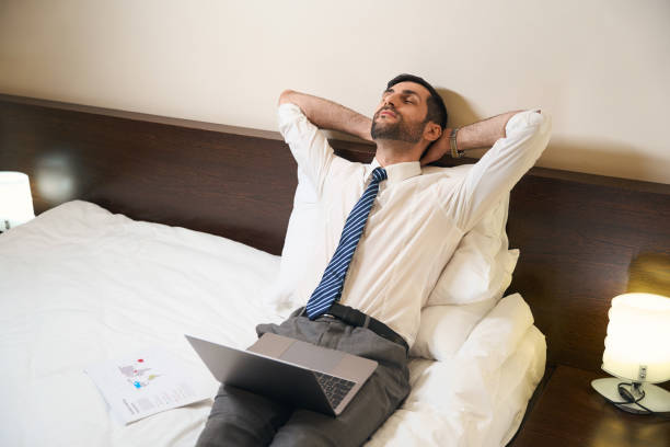 istock Man closed eyes from fatigue, he, without undressing, works in bed 1494044122