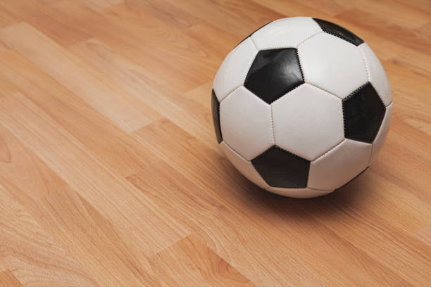 A white and black colored soccer ball isolated over a parquet floor