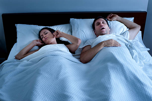 ronquido hombre con esposa en la cama - apnea del sueño fotografías e imágenes de stock