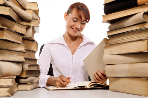 Beautiful young woman with stack of books on white background