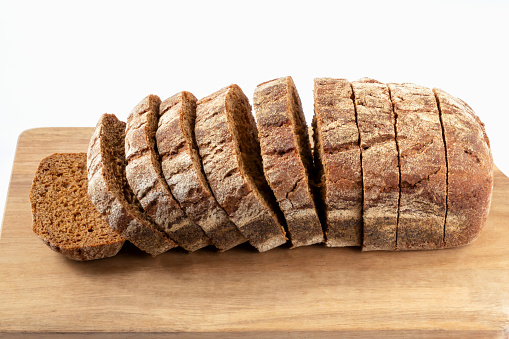 Sliced fresh baked loaf of bread on wooden board on white background. Top view