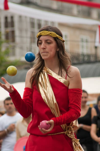 Lugo, Spain- June 28, 2009: Rear view of blonde young woman  juggling  with multi colored balls, wearing flower wreath. Traditional festival, Arde Lucus Roman Historical Reenactment. Lugo city, Galicia, Spain.