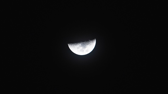 the moon is shown from behind in the dark sky and dark