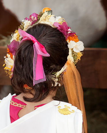 Rear view of  young woman with flower garland, white background. Traditional festival, Arde Lucus Roman Historical Reenactment. Lugo city, Galicia, Spain.