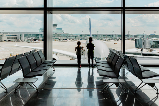 Excited children watching at the airplane parked on the terminal