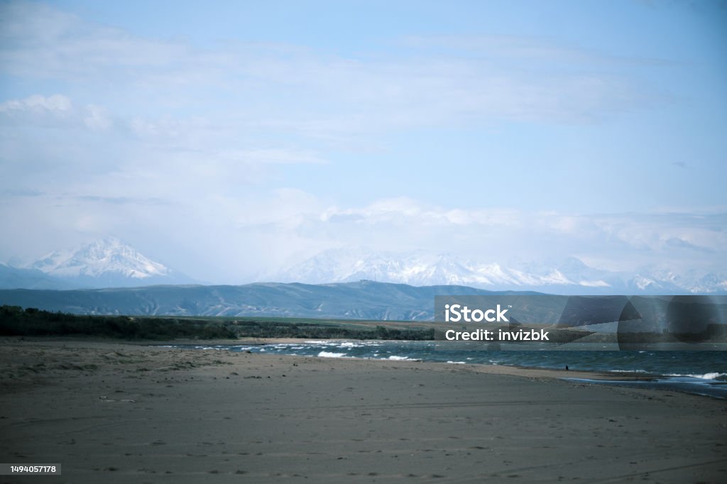 Beach of salt lake with mountain ridge and cloudscape on the background Bay of Water Stock Photo