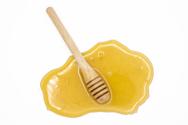 istock Honey dipper on spilled honey isolated on white background 1494057212