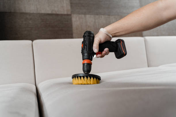 istock Close-up applying detergent on sofa in home interior for dry cleaning. Smearing detergent on couch using drill with brush for dry cleaning. 1494060243