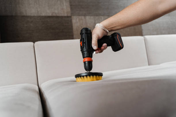 istock Close-up applying detergent on sofa in home interior for dry cleaning. Smearing detergent on couch using drill with brush for dry cleaning. 1494060246