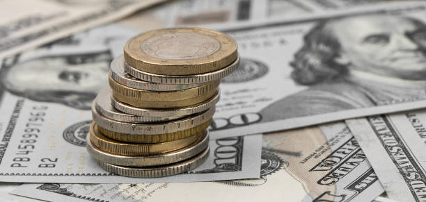 istock Stack of golden coins on dollar bills on a table. 1494060363