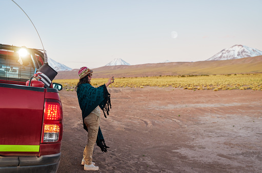mid adult brunette tourist woman taking photos with her cell phone at the roadside in San Pedro de Atacama