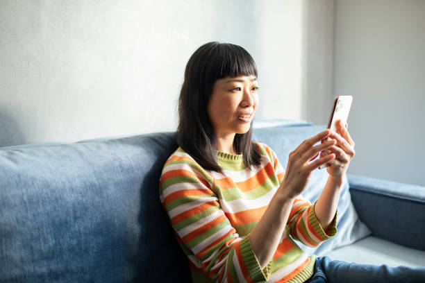 istock Young Japanese Woman using a smart phone at home 1494064059