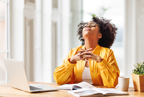 Frustrated tired young african american woman entrepreneur closed eyes with painful expression on her face, sitting in front of laptop  working remotely online. Frustrated ethnic female has computer problem