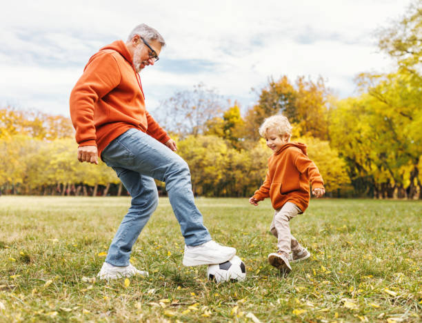 feliz abuelo y nieto de la familia juegan al fútbol en el césped del parque - people caucasian sport family fotografías e imágenes de stock