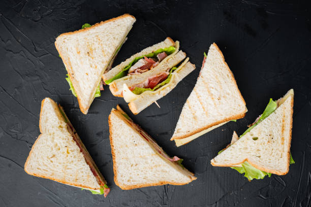 halves of fresh club sandwich, on black background, top view - sandwich club sandwich ham turkey imagens e fotografias de stock