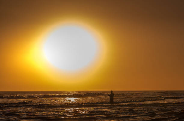 Man standing in the sea while fishing at sunset. Summer concept.