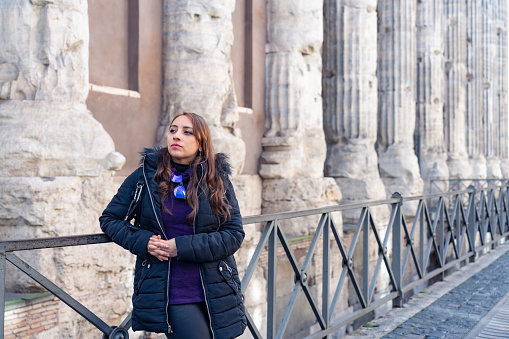 Contemplative young Latin woman tourist standing near Tempio di Adriano in Rome, Italy