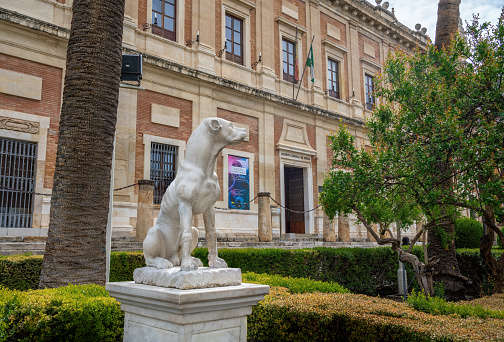 Seville, Spain - Apr 7, 2019: Dog Sculpture in front of General Archive of the Indies (Archivo General de Indias) - Seville, Andalusia, Spain