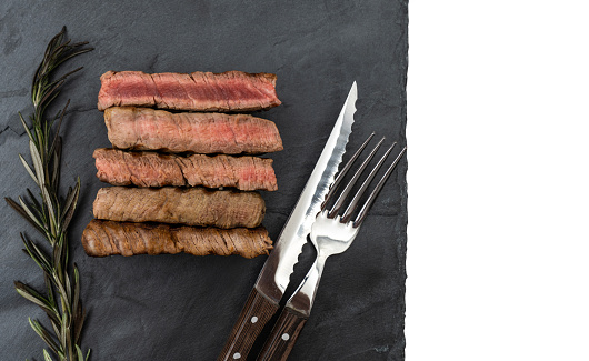 Slices of beef steak on slate.