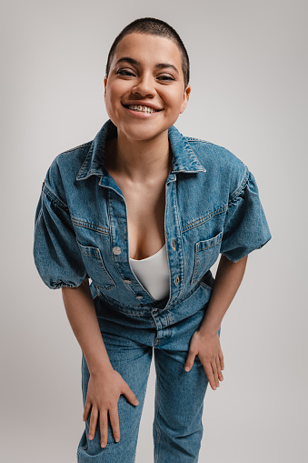 Happy short hair woman in denim clothes looking at camera against grey background