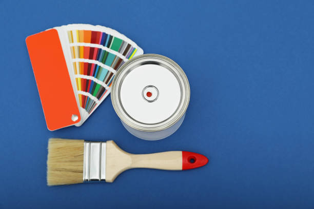 istock Can of orange paint, color palette samples and brushes on blue background. Space for text 1494092690