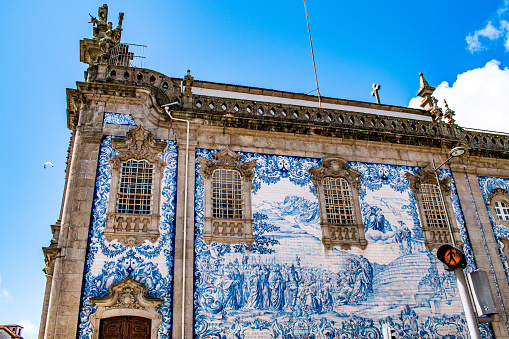 Fully-tiled facade of Carmo Church, a historic baroque church in Porto, Portugal, with azulejos tiles against a blue sky