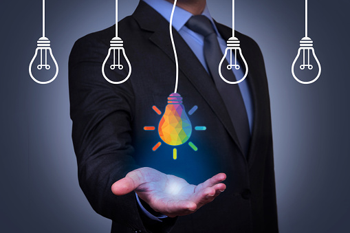 To remind the importance of innovation in the business world. Businessman holds in his hand a light bulb. New idea in human palm. To be ordinary or different. Innovation brings success.