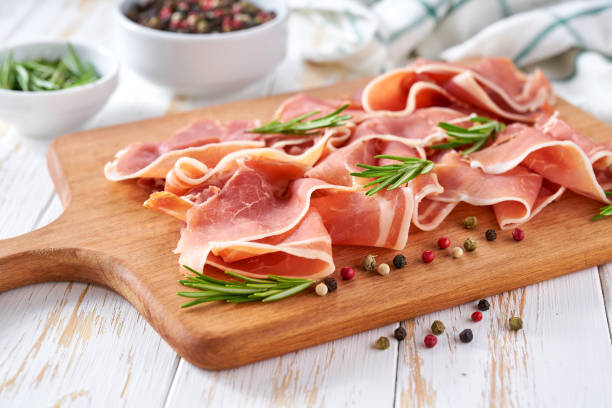 traditional prosciutto di parma with fresh rosemary on a wooden table. stock photo
