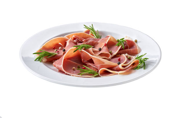 Spanish jamon cut, parma ham cutting with rosemary and spice in a plate isolated on white background. stock photo
