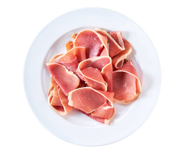 Curled slices of delicious prosciutto  in a plate isolated on white background. stock photo