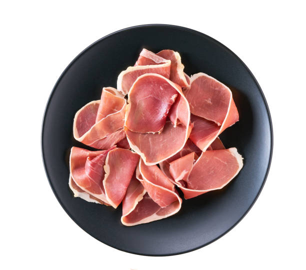 Spanish jamon cut, parma ham cutting in a black plate isolated on white background. stock photo