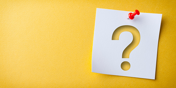 White Sticky Note With Question Mark And Red Push Pin On Yellow Cardboard